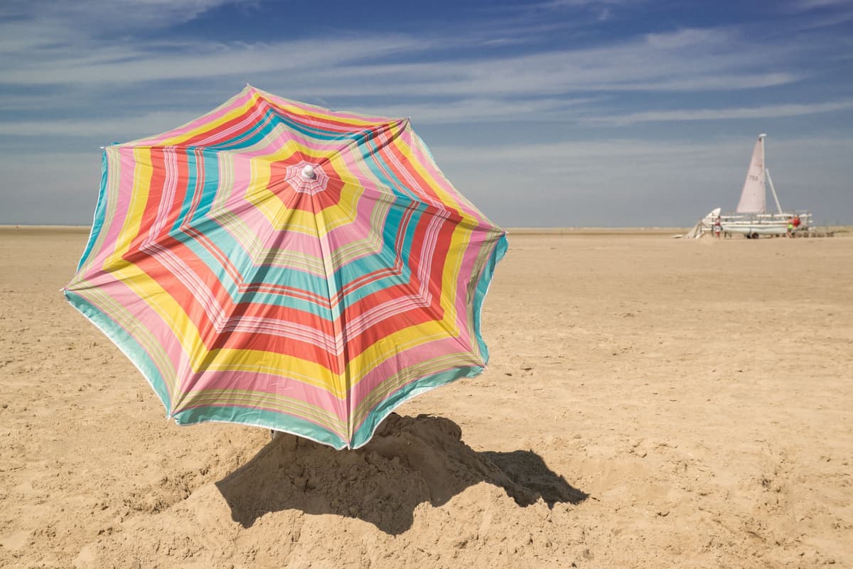 A beach umbrella open on the sand
